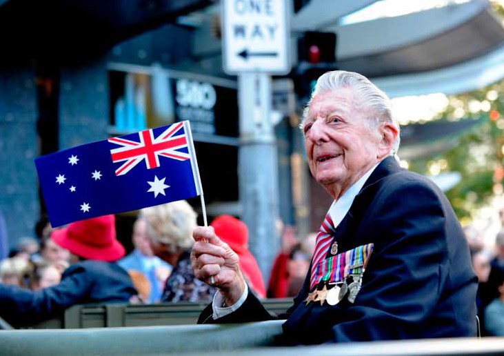 a veteran wearing medals holding the australian flag.