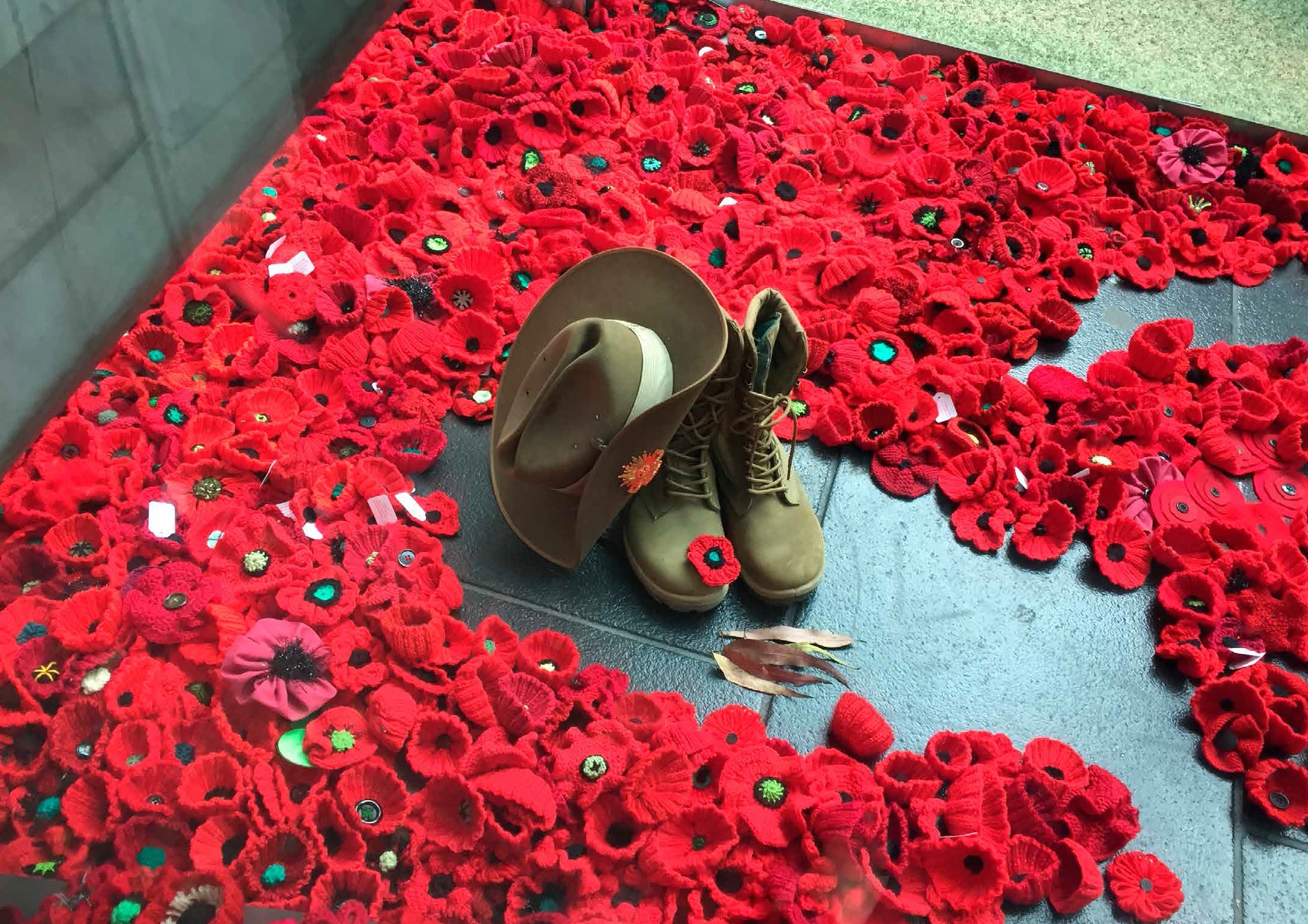 military boots and hat together in the middle of poppies.