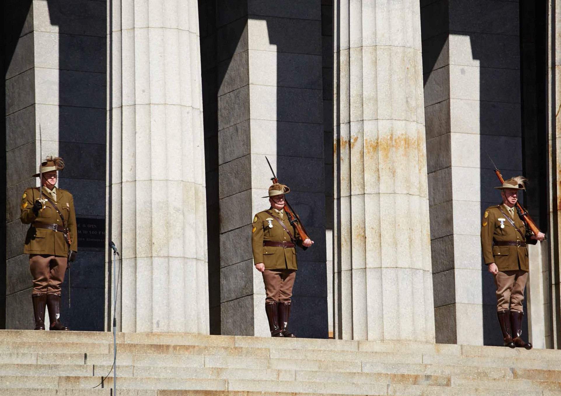 soldiers standing at the top of the shrine of rememberance stairs dressed in full military uniform.